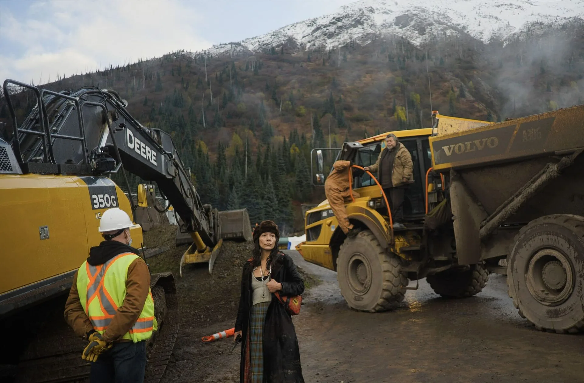 A Wet'suwet'en supporter and a private security contractor look on as Likhts'amisyu hereditary chief Dsta'hyl disables heavy machinery at a Coastal GasLink pipeline worksite. Photo Credit: Micheal Toledano. Copyright YINTAH FILM LTD.